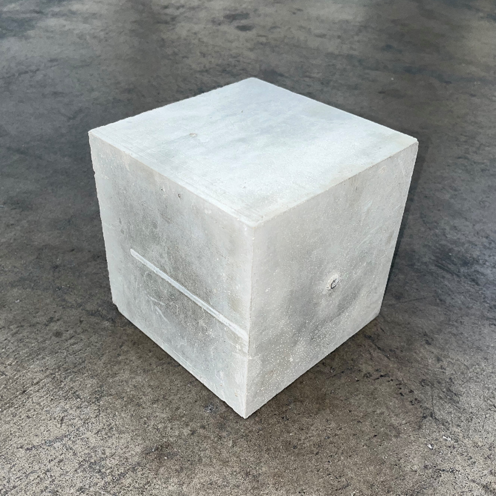 Einzelner grauer Betonblock mit strukturierter Oberfläche auf weißem Hintergrund