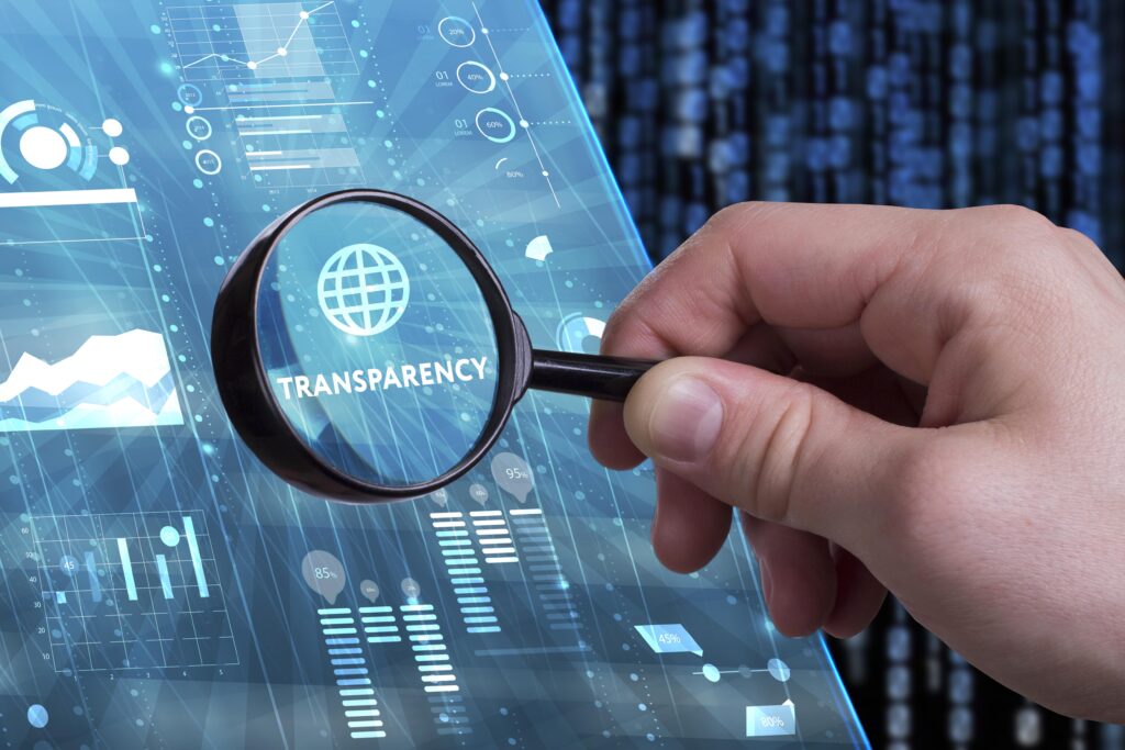 Hand hält eine Lupe über das Wort "Transparency" auf einem digitalen Interface mit Daten und Grafiken